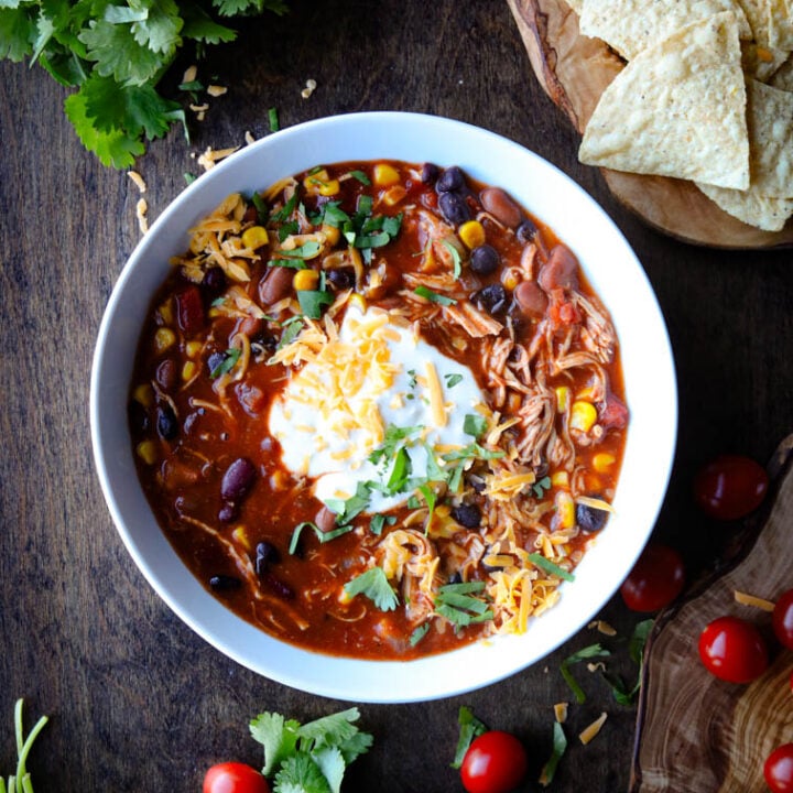 Bowl of Chicken Taco Soup topped with sour cream, shredded cheese, and cilantro.
