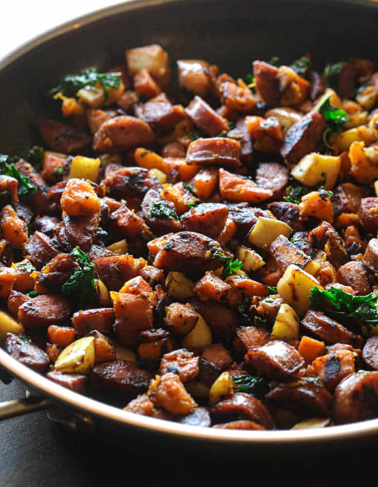 Chicken Sausage Sweet Potato Breakfast Hash in a big pot, with pieces of apple and kale.