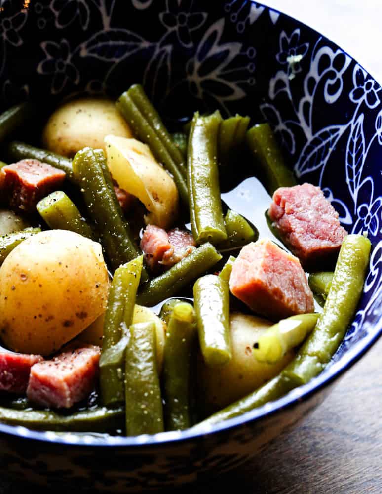 Crock pot green beans ham and potatoes cooked in chicken broth and served in a bowl