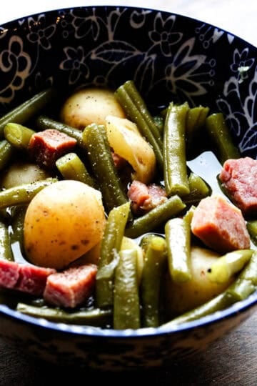A bowl of ham, green beans, and baby potatoes in broth